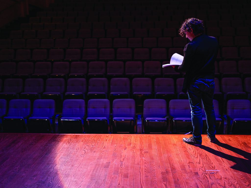 man standing on stage in front of empy theater