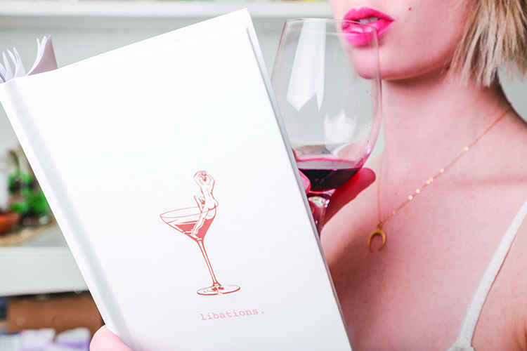 up close image of female drinking a glass of wine while looking at a menu